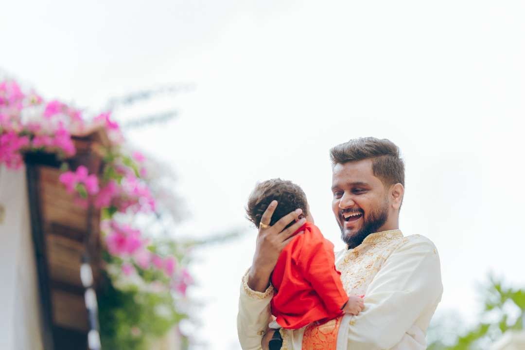 A father holding his baby during a naming ceremony, photographed by 35 Frames